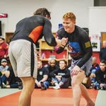 Jake, head coach at Last Round Martial Arts, smiling and clasping hands with a training partner on the mat after training.